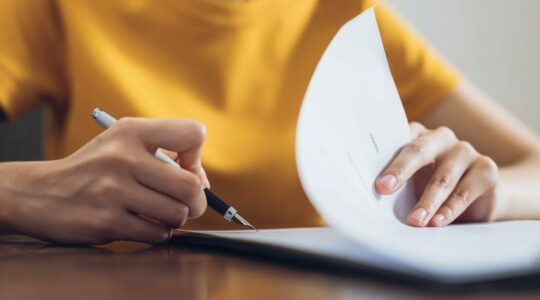 Getty Images 1167579980 Woman signing document color 1100x550